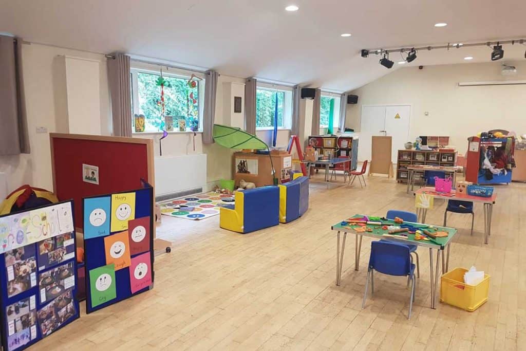 Colorful preschool classroom with toys, activity stations, and learning spaces for young children.