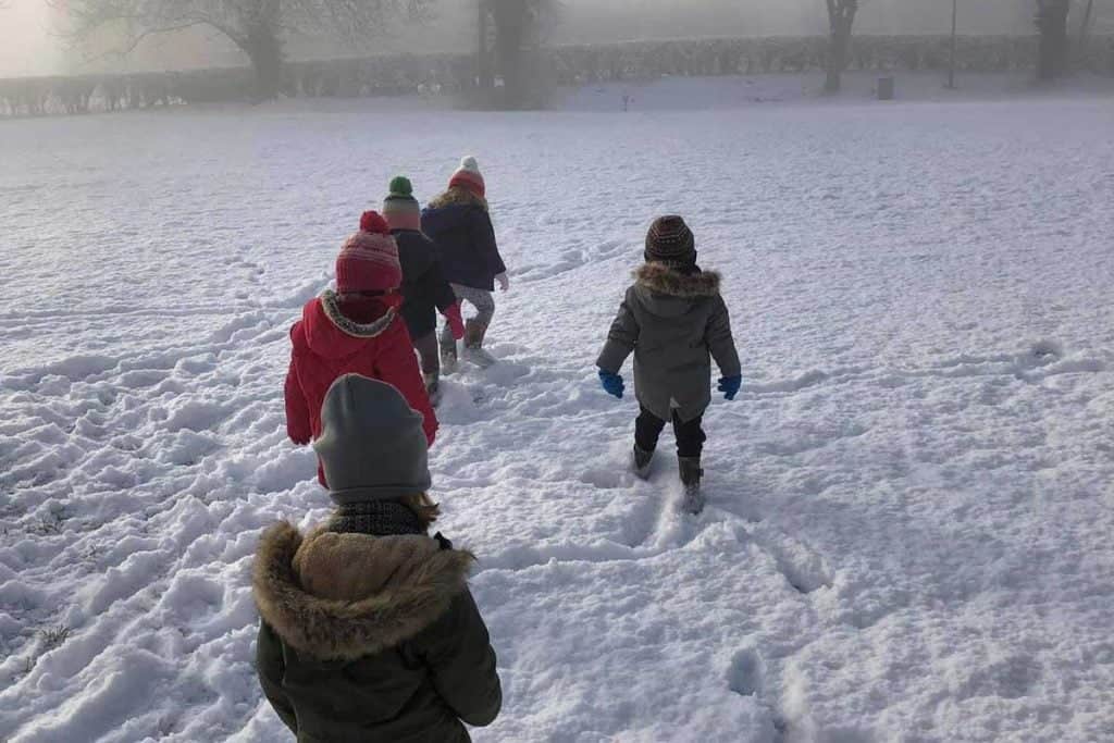 Children exploring snow outdoors at preschool.