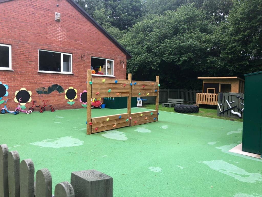 Outdoor play area at Whitley Community Preschool with climbing wall and toys.